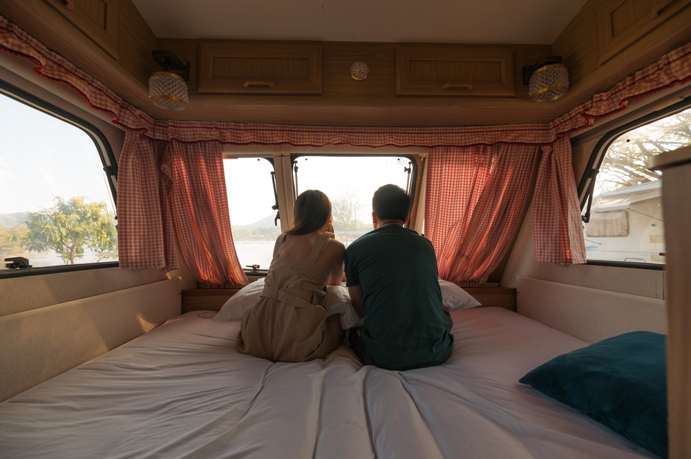 Young couple sitting and taking a view on mattress inside of cam